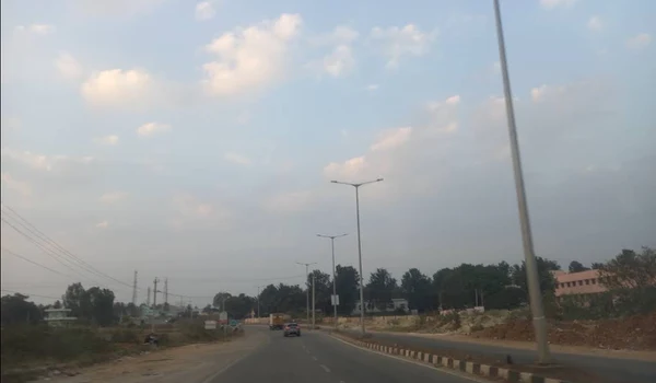 The Kannuru - Bagaluru Road with street lighting and open land alongside, North Bangalore
