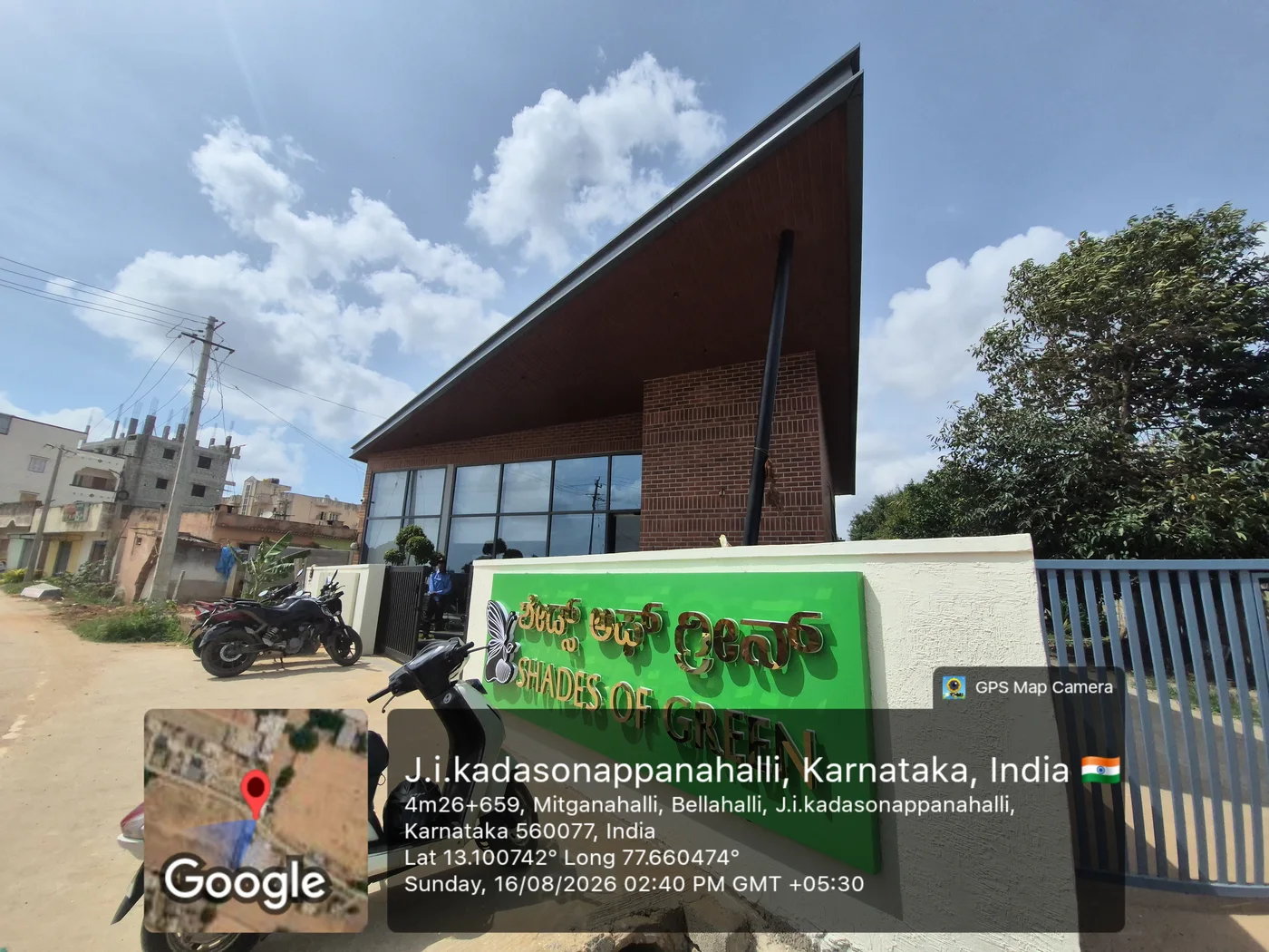 The HPR Shades of Green sales office at Kadusoppanahalli, a brick building with a cantilevered roof and the project signage in Kannada and English