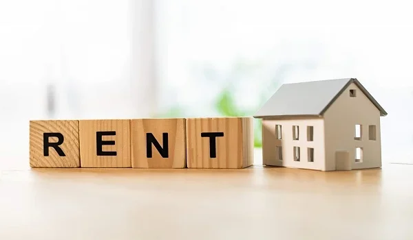 Wooden blocks spelling Rent beside a model house
