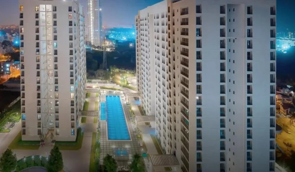 Residential towers lit at dusk with a swimming pool between them, representing North Bangalore housing